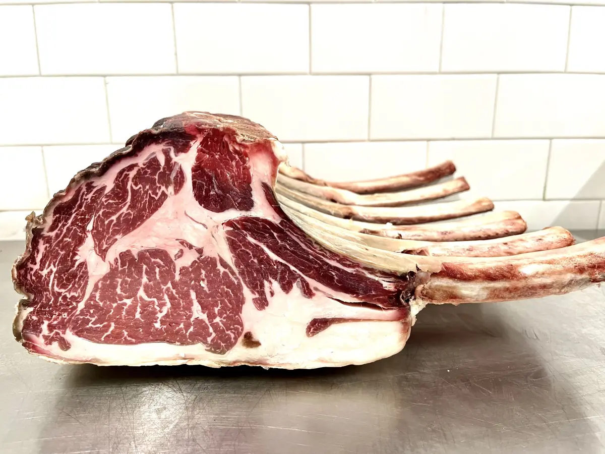 Tomahawk steaks aging on racks in the Macelleria dry-aging chamber