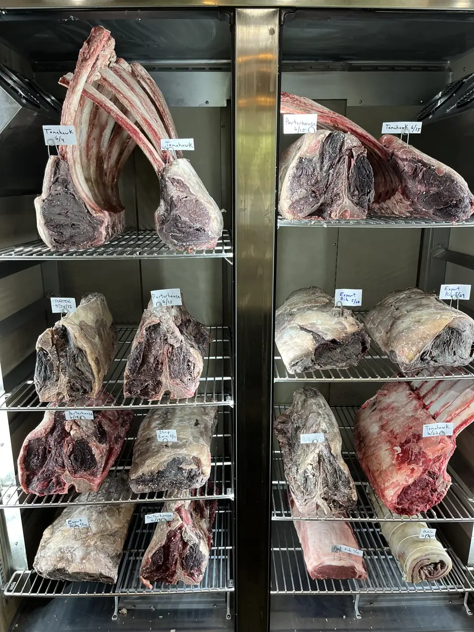 Beef dry aging on steel racks inside the chamber at Macelleria